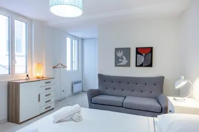 a white bedroom with a bed and a couch at The Apartment with the Garden Studio in Nice