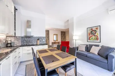 a kitchen and living room with a table and a couch at The Apartment with the Garden Studio in Nice