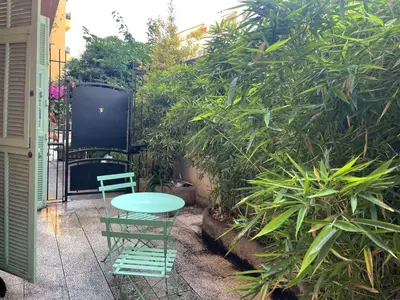 a table and a chair in front of a garden at Beautiful studio with terrace - Nice Liberation in Nice