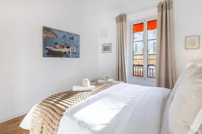 a white bedroom with a bed and a window at Appartement Assalit Two bedrooms in Nice in Nice