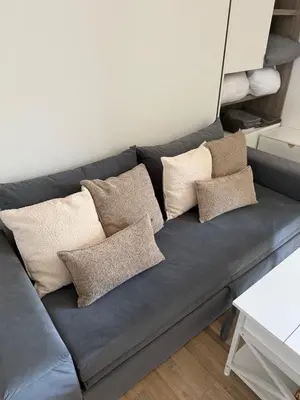 a blue couch with pillows on it in a room at Air-conditioned studio comfort & cozy in Saint-Laurent-du-Var