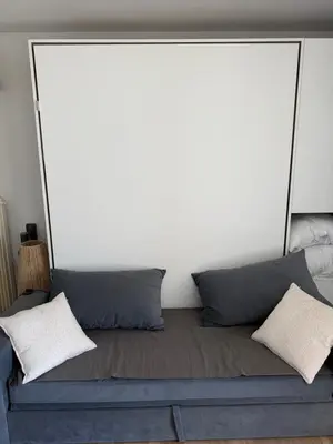 a bed with two pillows and a white wall at Air-conditioned studio comfort & cozy in Saint-Laurent-du-Var