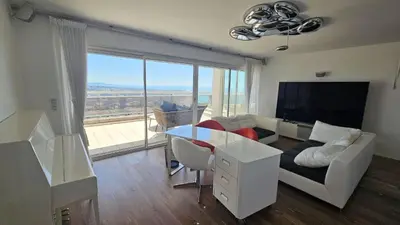 a living room with a couch and a table at Penthouse - Vue mer panoramique - SPA privé - Piscine commune in Saint-Laurent-du-Var