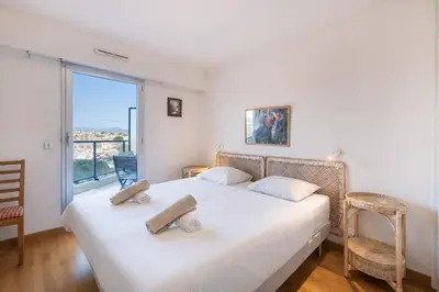 a bedroom with a large white bed and a large window at 2BR Sea View Apartment with Pool & AC in Cagnes-sur-Mer