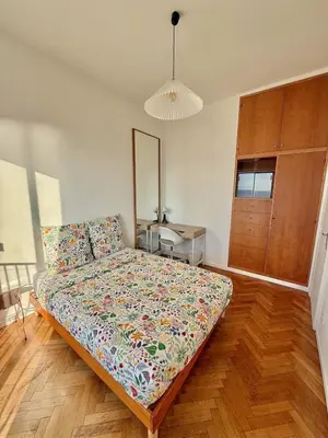 a bedroom with a bed with a floral comforter at Vue mer panoramique, plage et Promenade à pied in Nice