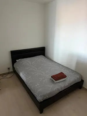 a bed with a black frame and a red blanket on it at Appartement 3 chambres avec piscine et parking privé in Nice