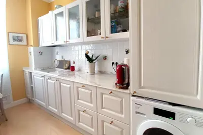 a kitchen with white cabinets and a washing machine at Large bright apartment in the heart of Nice in Nice