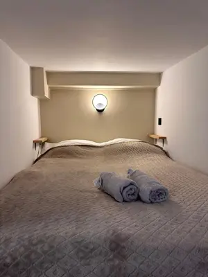 a bed with two towels on it with a clock on the wall at Charmant Studio Proche Plage et Transport in Saint-Laurent-du-Var