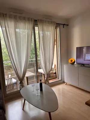 a living room with a table and a television at Charmant Studio Proche Plage et Transport in Saint-Laurent-du-Var