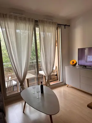 a living room with a table and a television at Charmant Studio Proche Plage et Transport in Saint-Laurent-du-Var