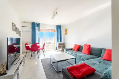 a living room with a couch and a table with red pillows at Le Concorde in Saint-Laurent-du-Var
