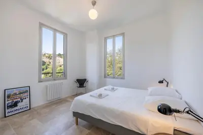 a white bedroom with a bed and windows at House on the Hill in Nice