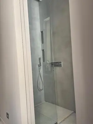 a shower stall with a glass door with a shower at Chambre Gounod in Nice