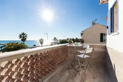 a balcony with a table and chairs overlooking the ocean at La Maison Du Pêcheur in Cagnes-sur-Mer