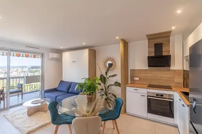 a kitchen and living room with a table and a blue couch at Studio cosy Vue mer in Nice
