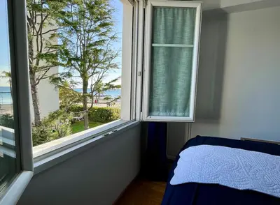 a bedroom with a window with a view of the ocean at Appartement Pieds dans l'eau in Saint-Laurent-du-Var