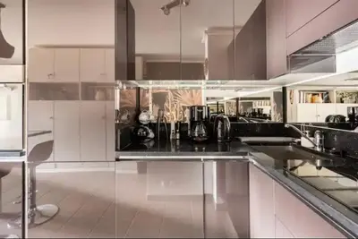 a kitchen with white cabinets and a black counter top at Carpe Diem in Beaulieu-sur-Mer