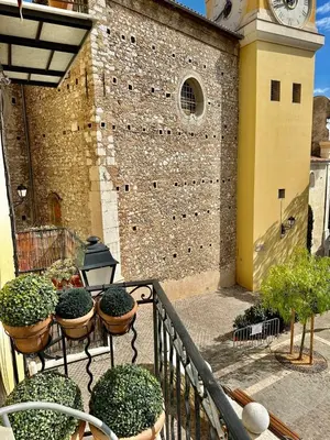 a balcony with potted plants and a clock tower at Résidence Place Poullan in Villefranche-sur-Mer