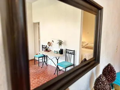 a mirror reflecting a room with a table and chairs at Résidence Place Poullan in Villefranche-sur-Mer