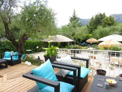 a patio with chairs and tables and an umbrella at Hotel mon Soleil in La Gaude