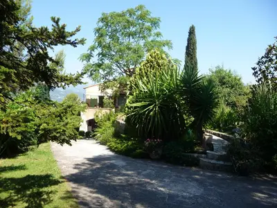 a house with trees and plants in a driveway at Appartement Castagniers in Castagniers
