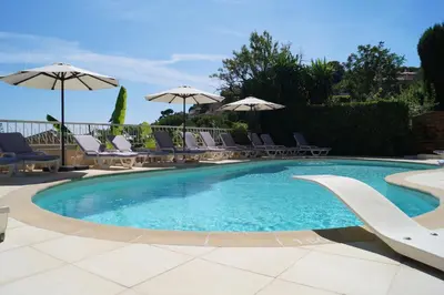 a large swimming pool with chairs and umbrellas at Hôtel La Fiancée du Pirate in Villefranche-sur-Mer