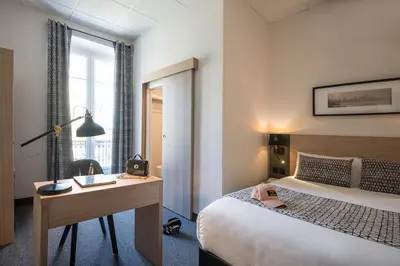 a hotel room with a bed and a desk and a window at Hotel Saint Gothard in Nice