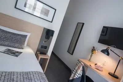 a bedroom with a bed and a desk with a tv at Hotel Saint Gothard in Nice