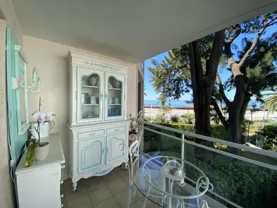 a balcony with a white cabinet and a table at Appartement sur la Plage, Le Royal Beach in Saint-Laurent-du-Var