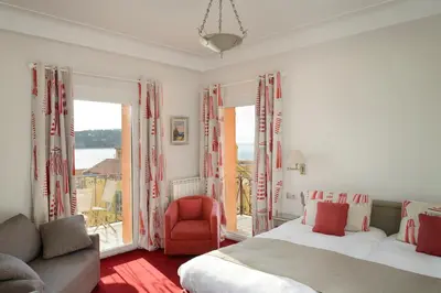 a bedroom with two beds and a red chair at Welcome Hotel in Villefranche-sur-Mer
