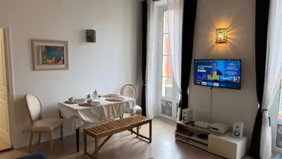 a living room with a table and a tv on a wall at 2 Bedrooms Appartement In Central Location on the famous Place Massena Nice in Nice