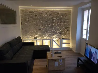 a living room with a couch and a stone wall at Nicolago in Nice