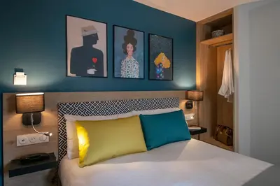 a bedroom with a bed with paintings on the wall at Bristol Nice in Nice