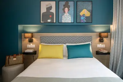 a bedroom with a bed with two pillows and paintings at Bristol Nice in Nice