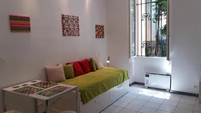 a small bedroom with a green bed with a window at Studio dans la Villa 