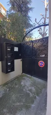 a black iron gate with a tree behind it at Studio dans la Villa 