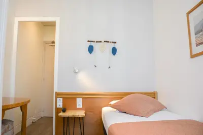 a small bedroom with a bed and a table at Hotel Busby in Nice
