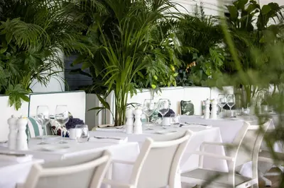 a table with white tables and chairs and plants at Hotel Le Negresco in Nice