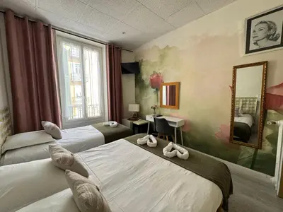 a hotel room with two beds and a mirror at Hotel des Dames in Nice