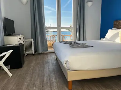 a bedroom with a bed and a large window at Hôtel du Bord de Mer 