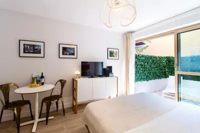 a bedroom with a bed and a table and a tv at CENTRE PROMENADE Golden Square Terrace 1 min Walk to the Beach AC in Nice