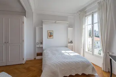 a white bedroom with a bed and a window at Penthouse Lou Lòu by iVillamia com in Nice