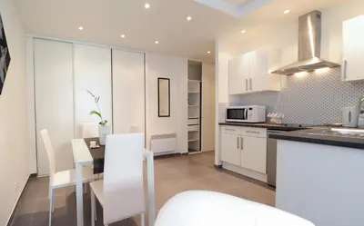 a kitchen with white cabinets and a table and a microwave at Suite Imperazur Five stars Holiday House in Nice