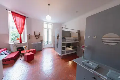 a living room with a red couch and a bed at La Maïoun Guesthouse in Nice