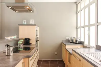 a kitchen with wooden cabinets and a large window at MY CASA - VEILLON - 2 bedrooms - City Center in Nice