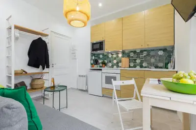 a kitchen with wooden cabinets and a table and chairs at Casa Madere- Idéal Couples - Central & cosy -Train station - Tram & Supermarkets-Balcony- Washing-machine-AC in Nice