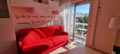 a red couch in a room with a balcony at Affitto-Nizza in Nice