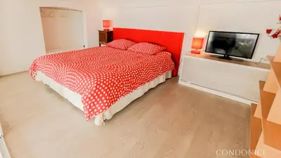 a bedroom with a red bed and a flat screen tv at CondoNice in Nice