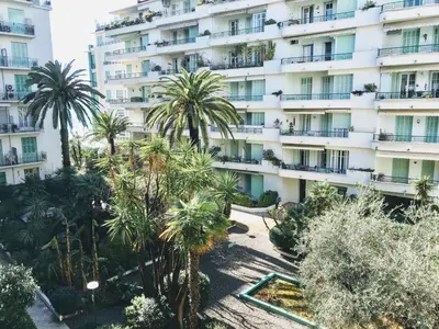 an apartment building with palm trees in front of it at Nice Beach - Promenade Des Anglais in Nice