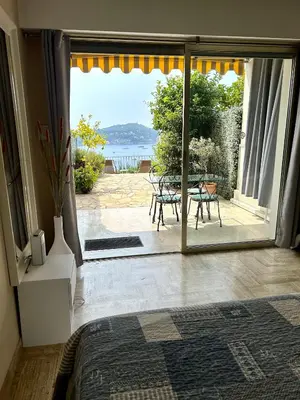 a bedroom with a door open to a patio with a table at Studio Leopolda in Villefranche-sur-Mer